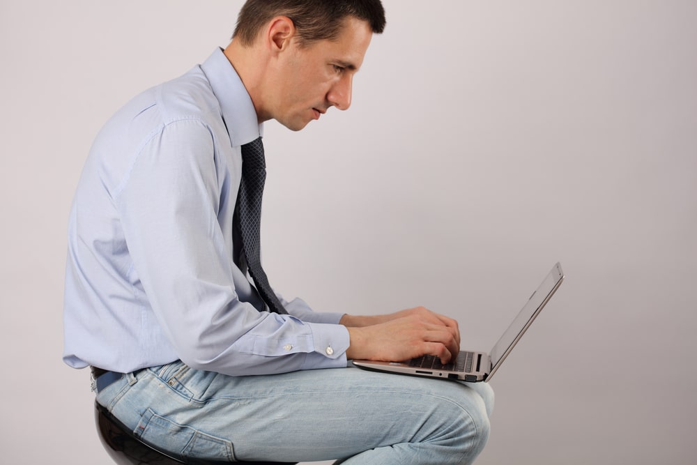 man slouching while using a laptop
